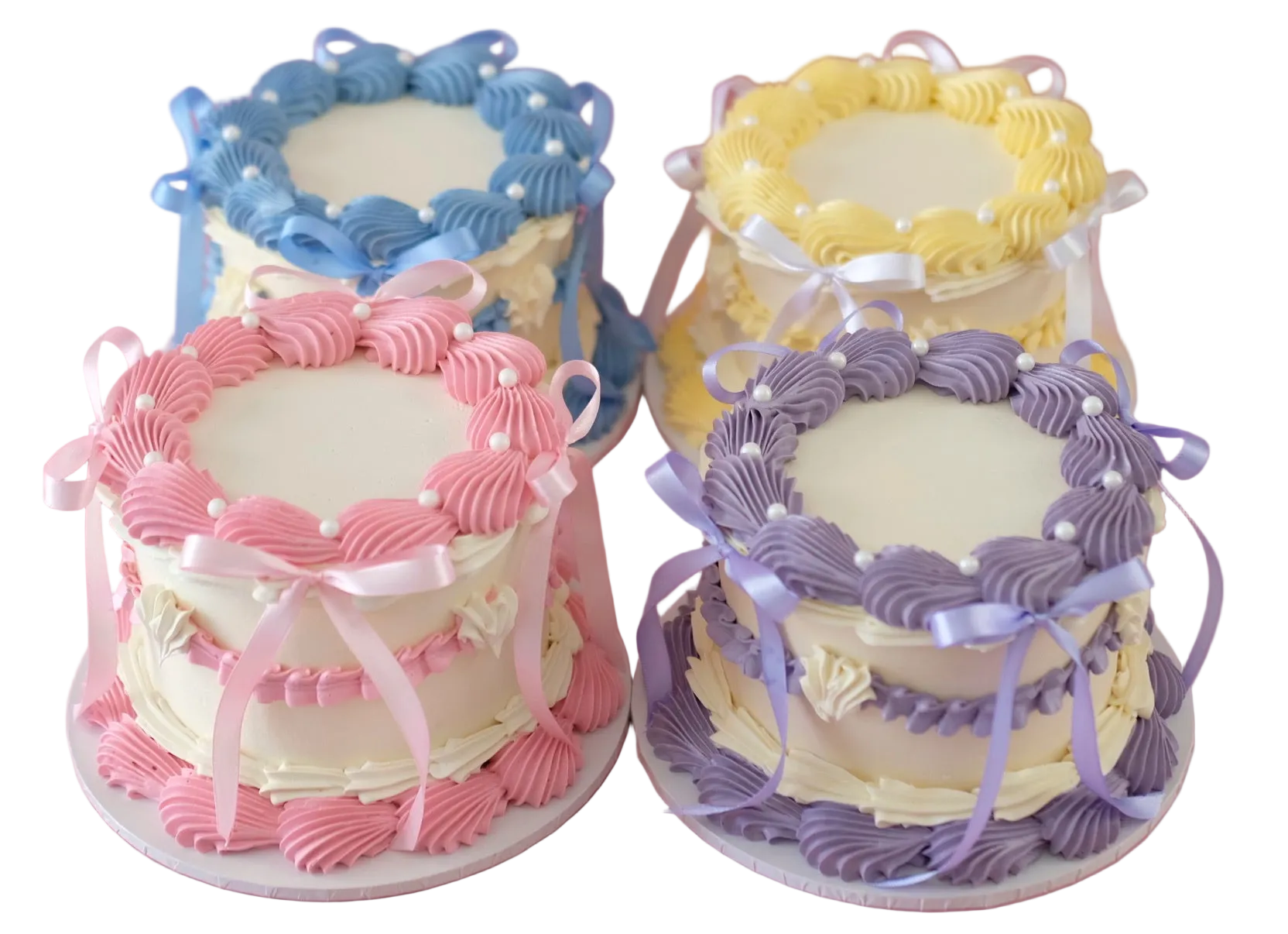 Four small decorated cakes in pastel colors on a white background